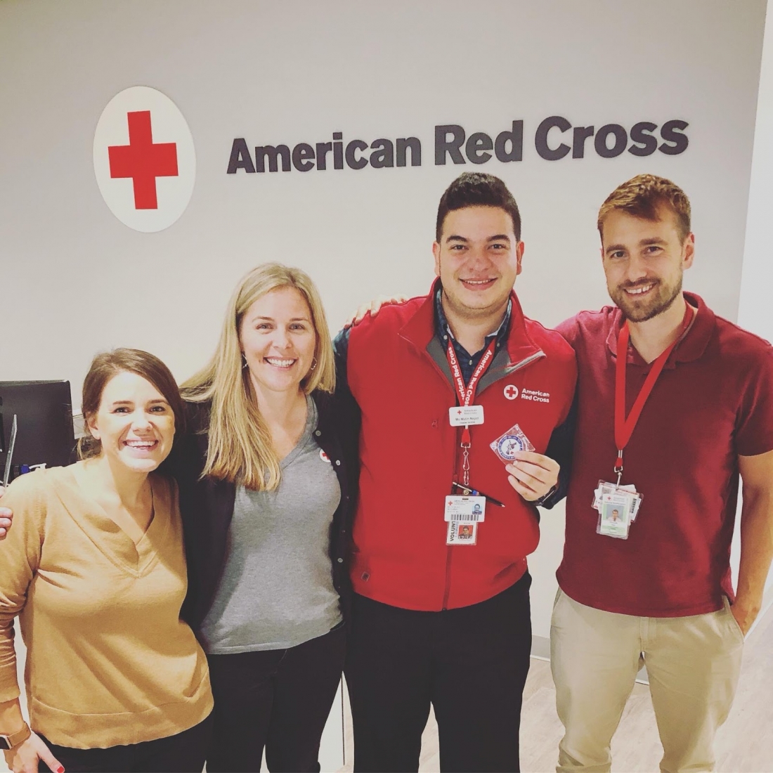 A group of four people posing for a photo in front of an "American Red Cross" logo. 