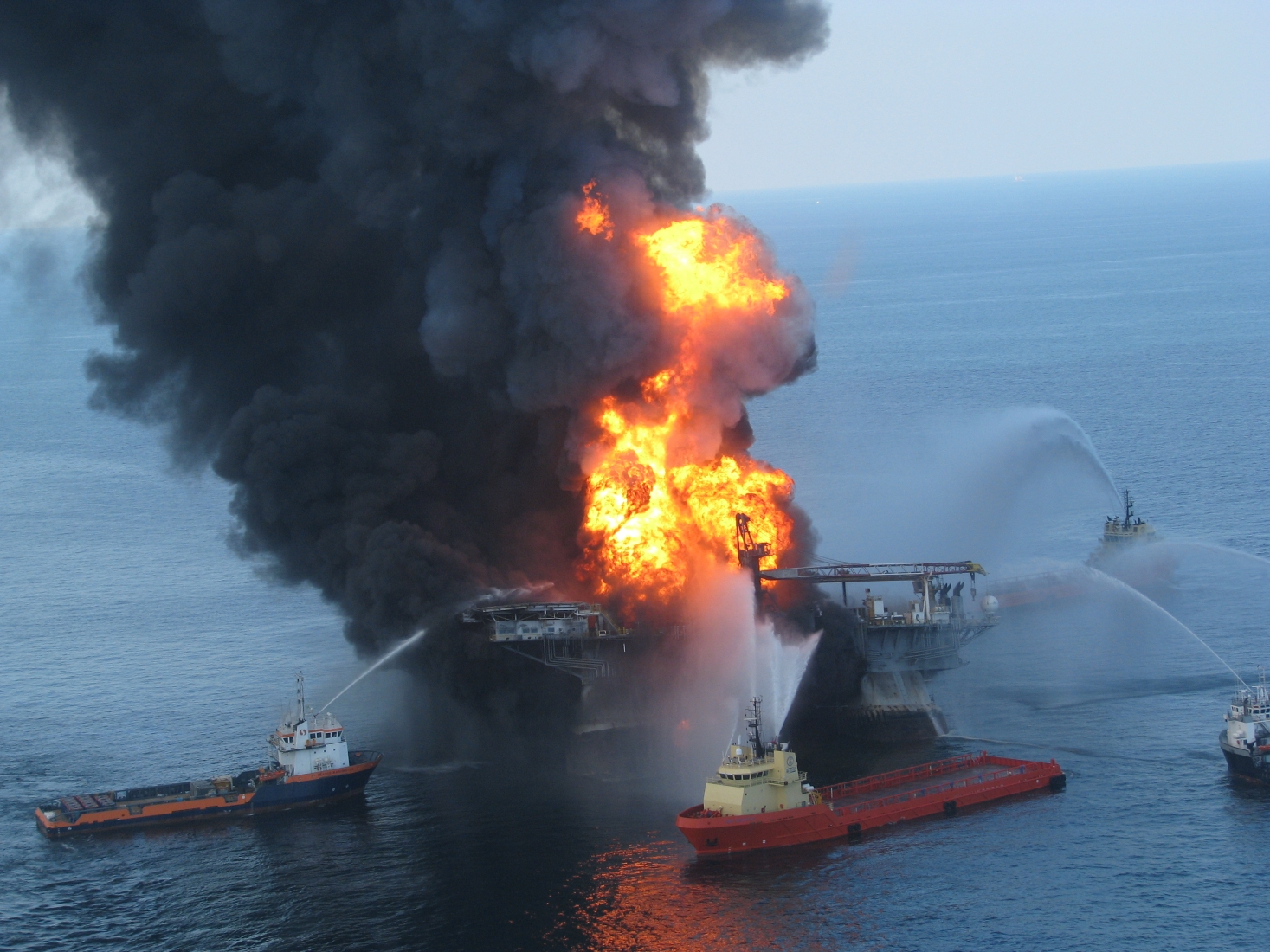 Several vessels pump pressurized water at a fire on an oil rig.