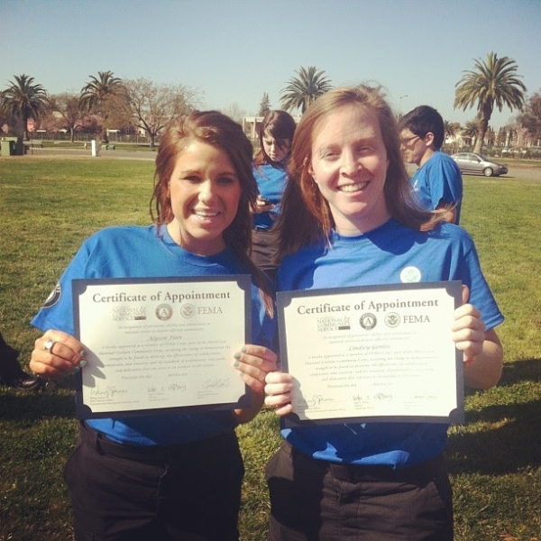 Two people holding "Certificates of Appointment" with a FEMA logo on it. 