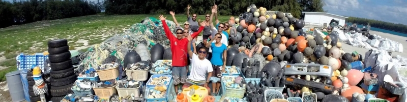 A group of people surrounded by a large trash pile. 