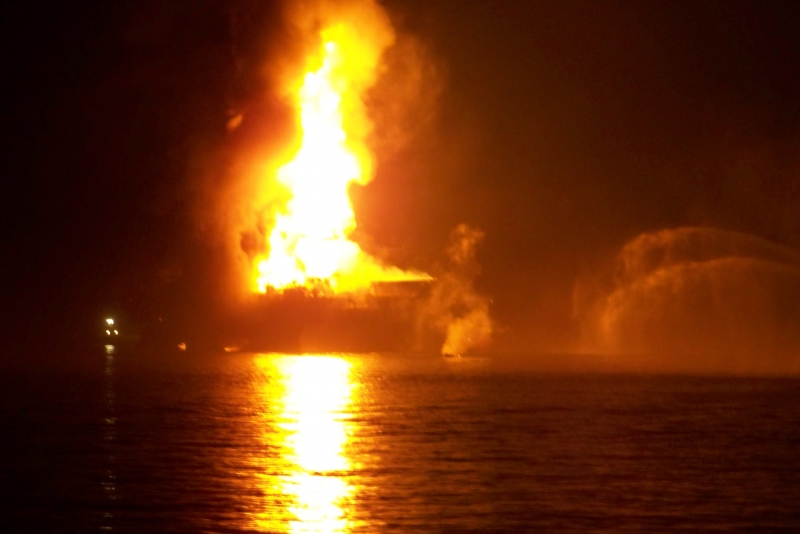 A dark and blurry image of an oil platform on fire. 