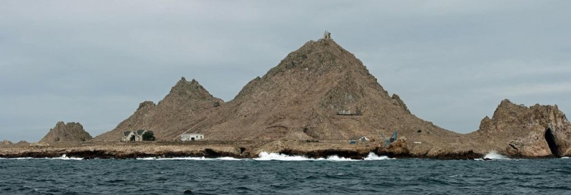A rocky island with three buildings visible. 