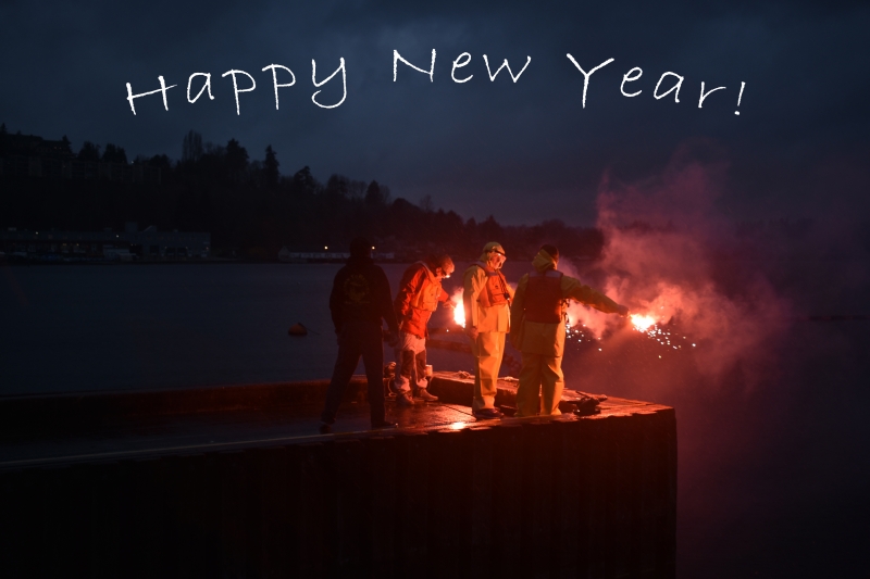 People in orange response gear standing on a dock holding flares. Above, the image reads "Happy New Year!"