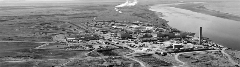 A black and white image of an industrial site on a river.