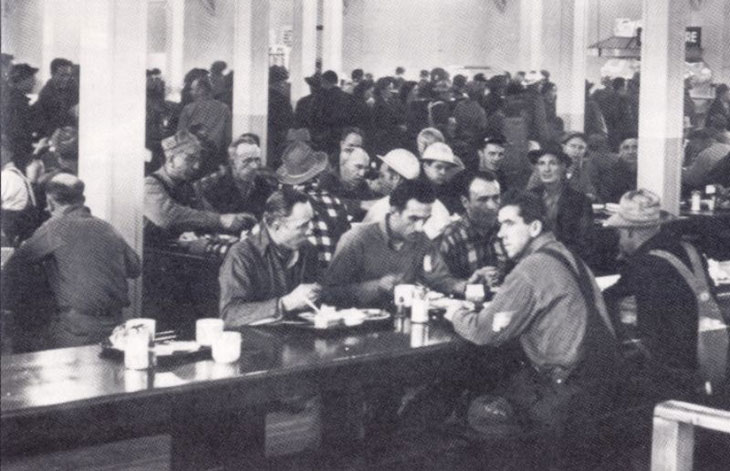 A black and white photo of workers in a cafeteria.