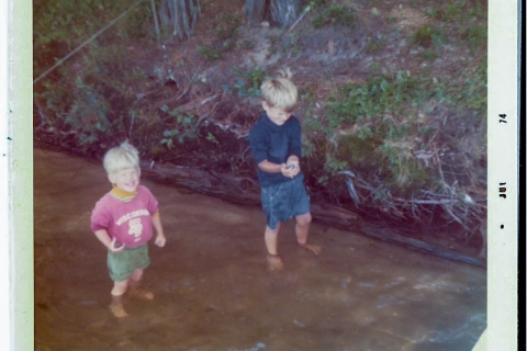 Two children standing in water.