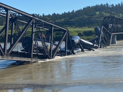 Railroad bridge collapsed in the water with tanker cars piled in the water.