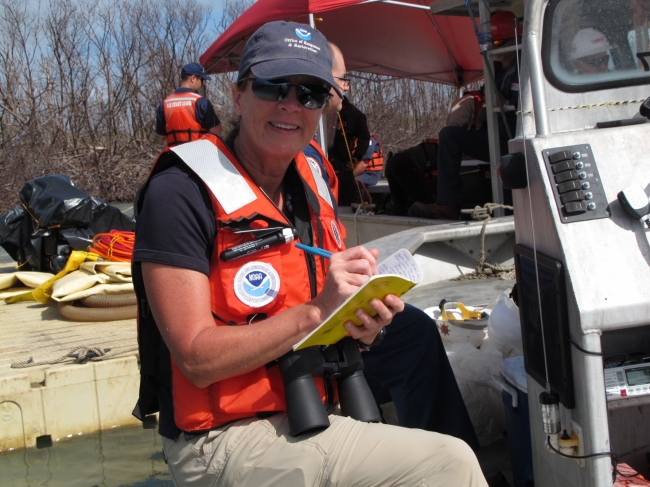 A woman in a life jacket writing in a notebook.