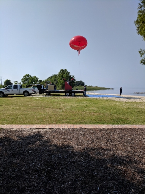 A large ballon-like object floating about a park area. 