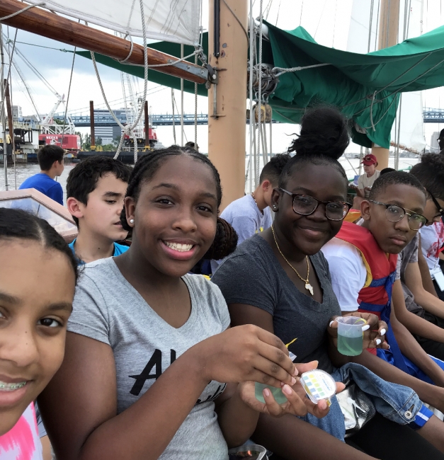 Group of teenagers aboard sailboat.