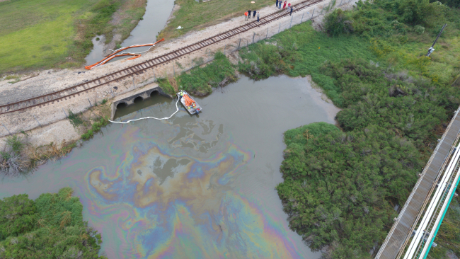 An aerial image of an oil sheen along a road in a marsh area.