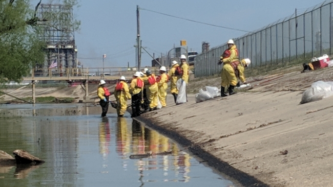 A cleanup crew working on an oiled concrete shoreline.