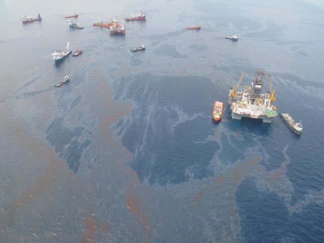 An aerial view of oil on water with various vessels. 