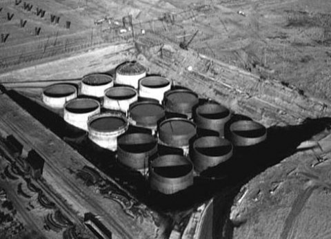 A black and white photo of large containers in the ground.
