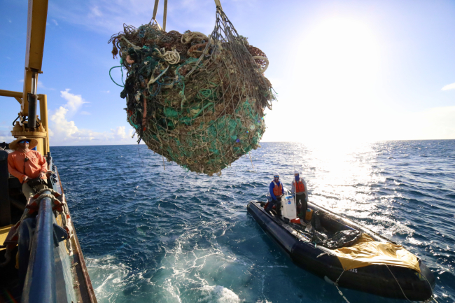 A large pile of derelict fishing net being hoisted from the water.