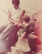 A father and his son fishing at a lake.