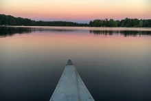 A sunset on a lake as seen from a kayak or a paddleboard.