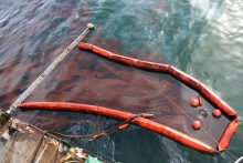 A skimmer surrounding an oil sheen in the water. 