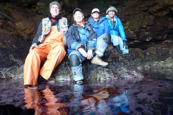 Four people pose together in a cave with water. 