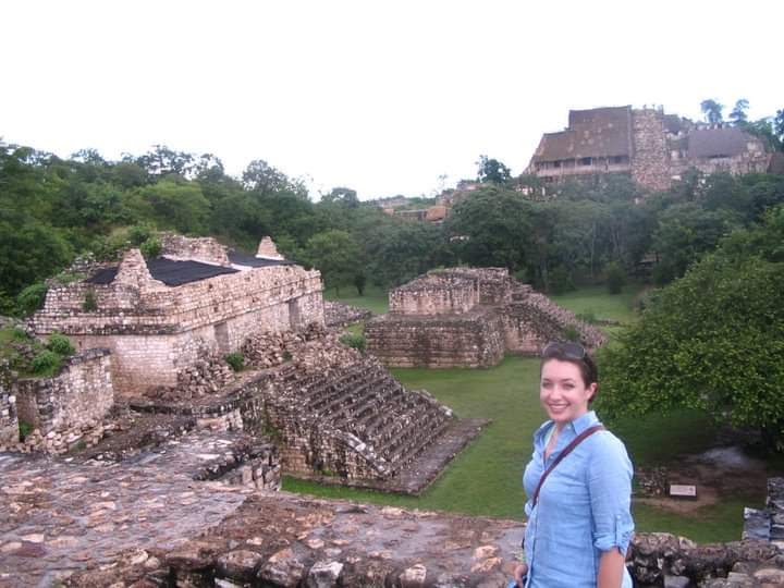 A person posing for a photo in front of ruins. 