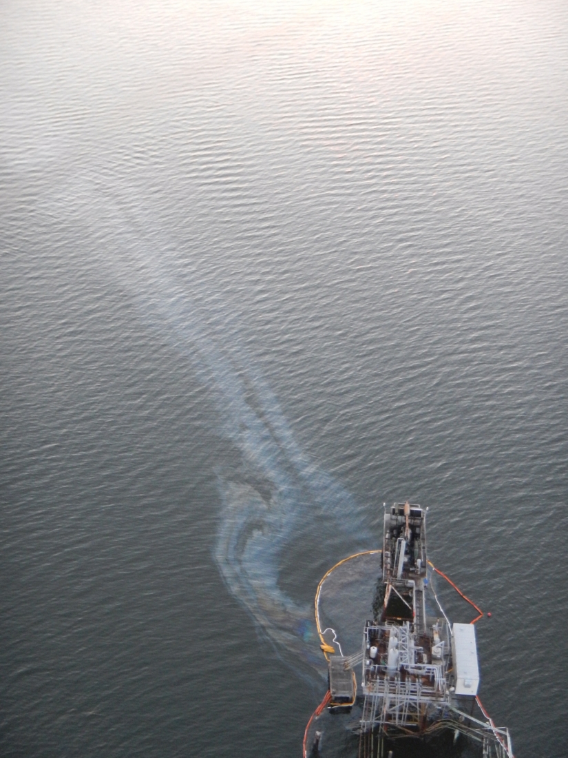 An oil sheen coming from an oil platform in water.