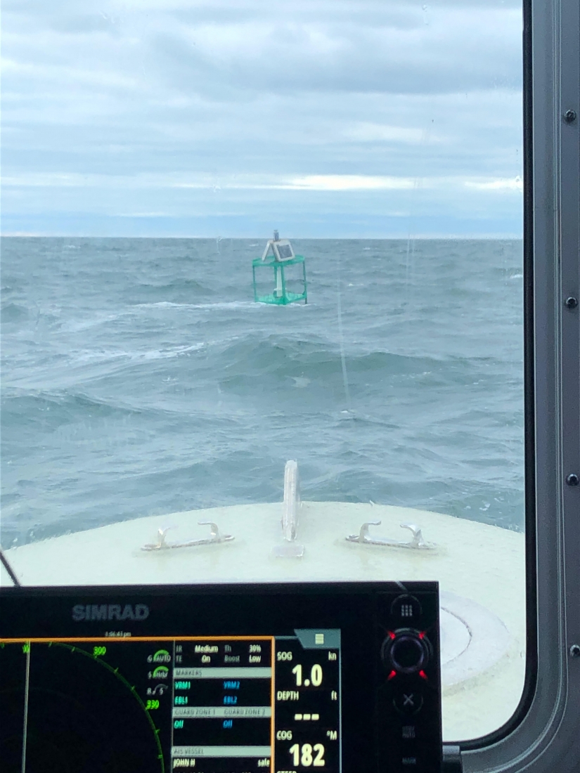 A buoy being hosted from the water as seen from a boat. 
