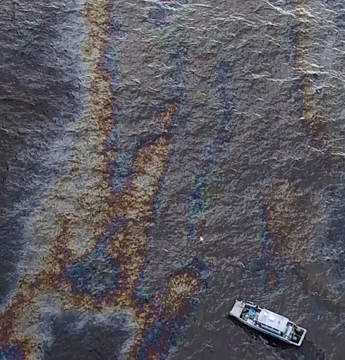 An aerial image of a boat in an oil sheen.
