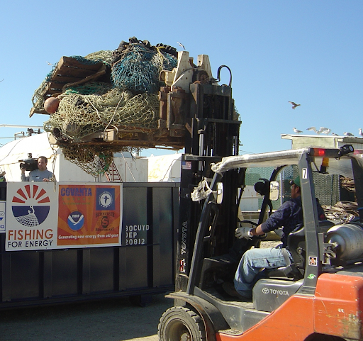 A forklift drops a load of old nets into a bin labeled "Fishing for Energy."