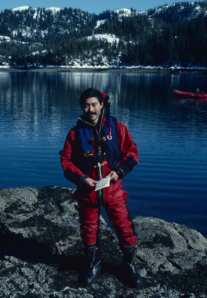 A man in response gear with a body of water and mountains in the background.