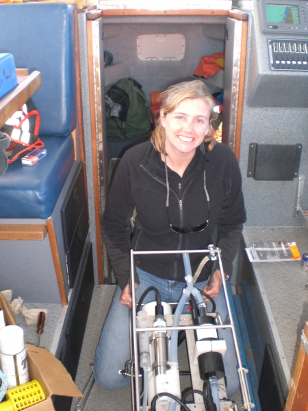 A woman sitting on a boat with gear in front of her.