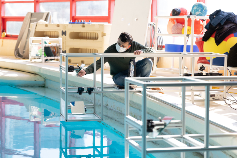 Two people setting up equipment alongside a pool.