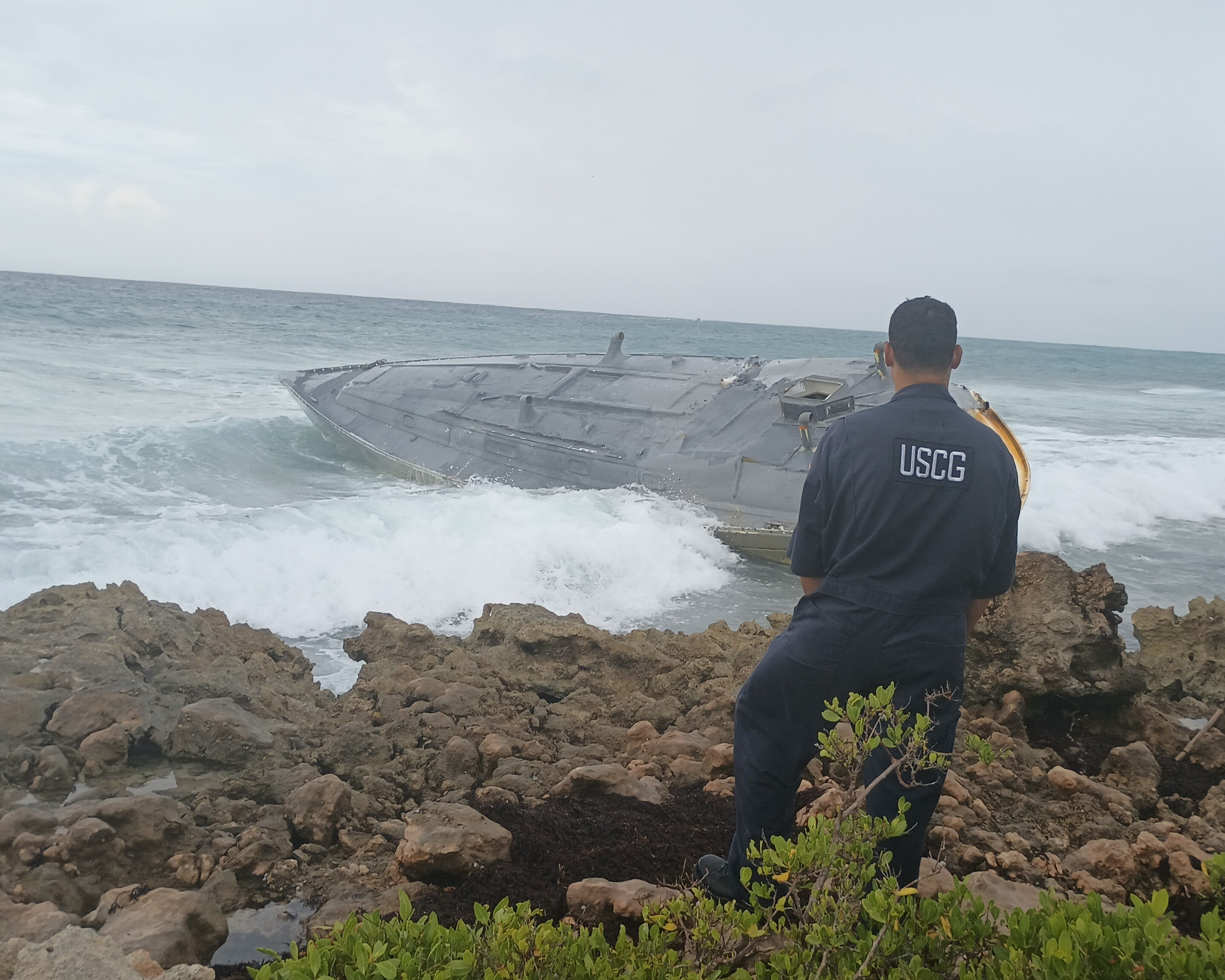 A Coast Guard Marine Science Technician responding to a pollution case inspects a derelict semi-submersible submarine on Sept. 4, 2023, after the vessel washed ashore on Mona Island, Puerto Rico.