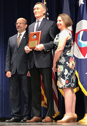 Two people presenting an award to a third. 