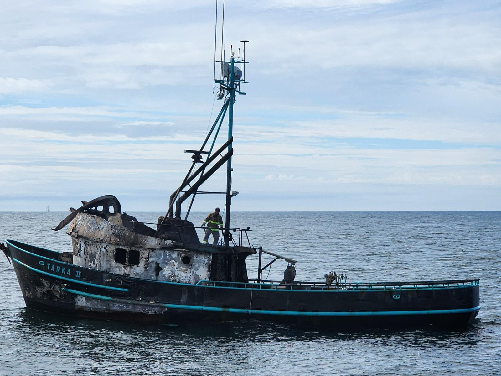 Responder is seen aboard the burned remains of a commercial crabbing vessel.