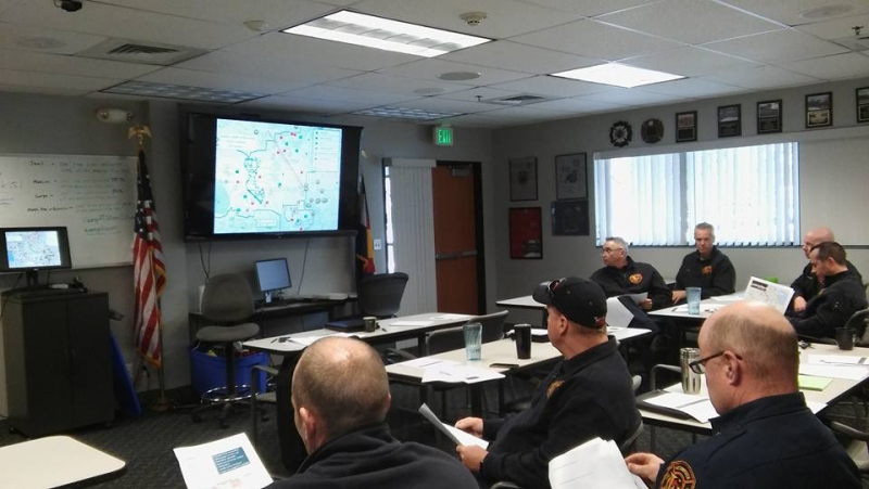 A group of people looking at a projector with a map on the screen. 