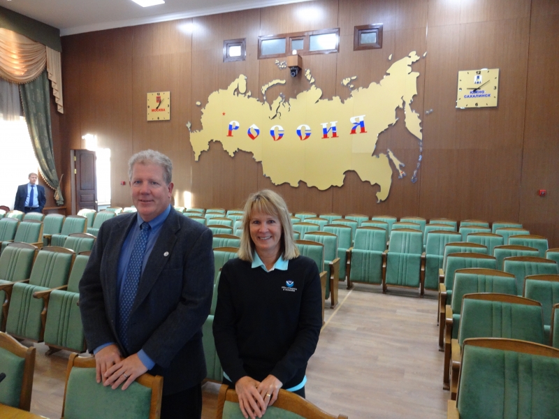 Two people posing for a photo in a meeting space.