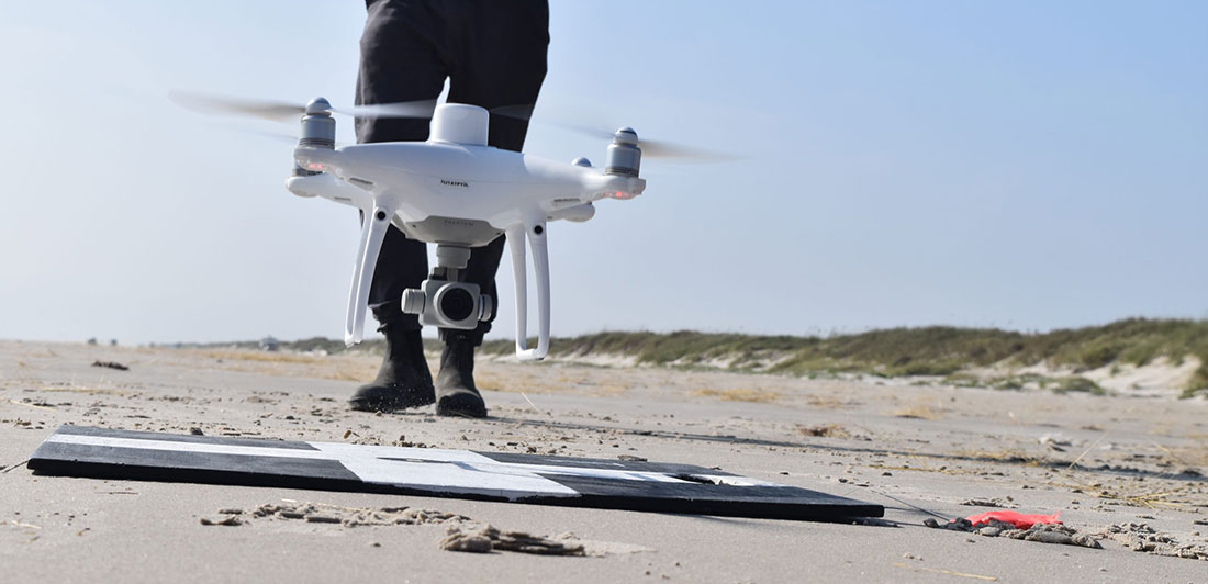 An uncrewed aircraft system (UAS) landing on a sandy beach.