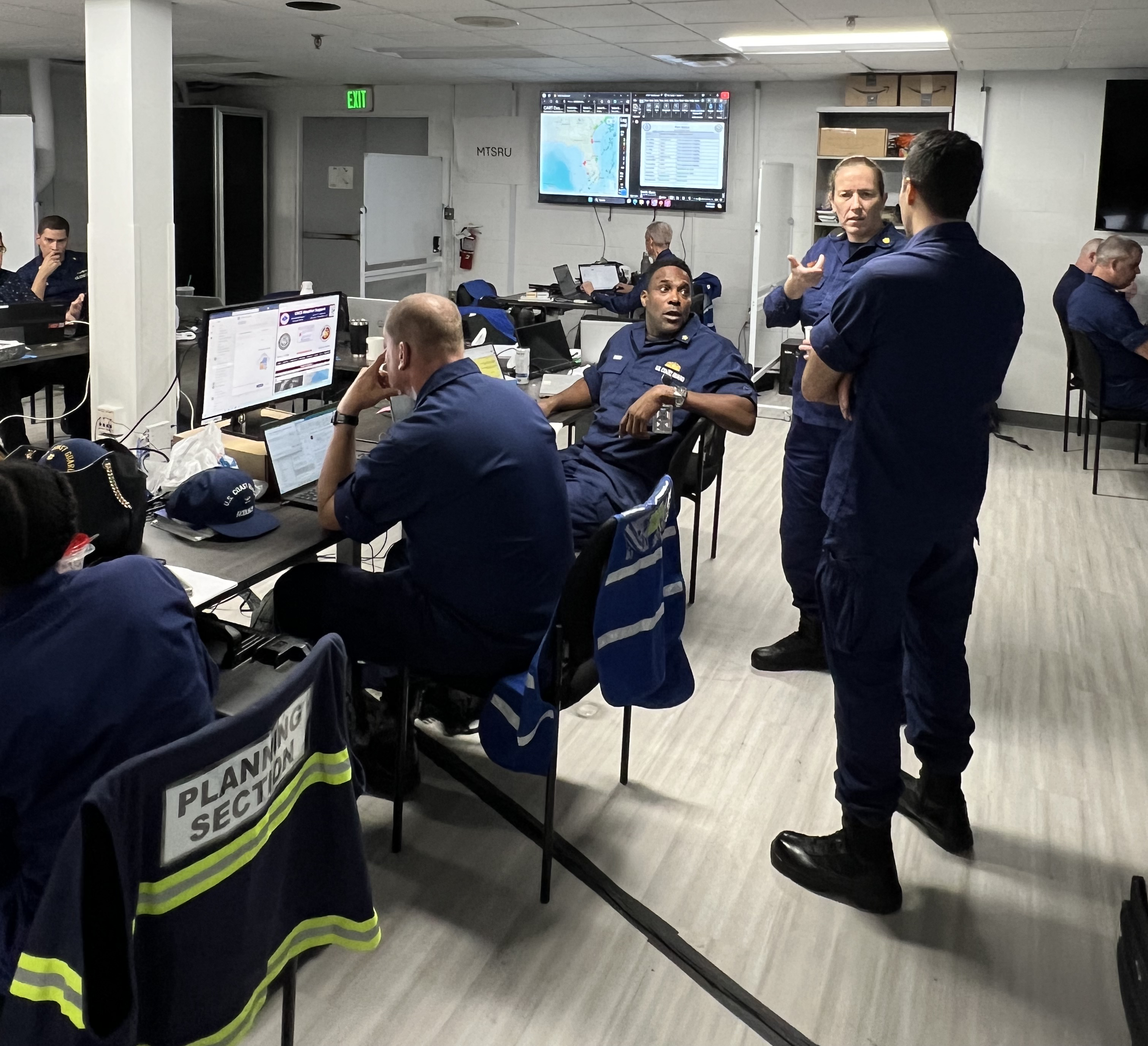 Uniformed Coast guard members work within an Area Command room to support hurricane response. 