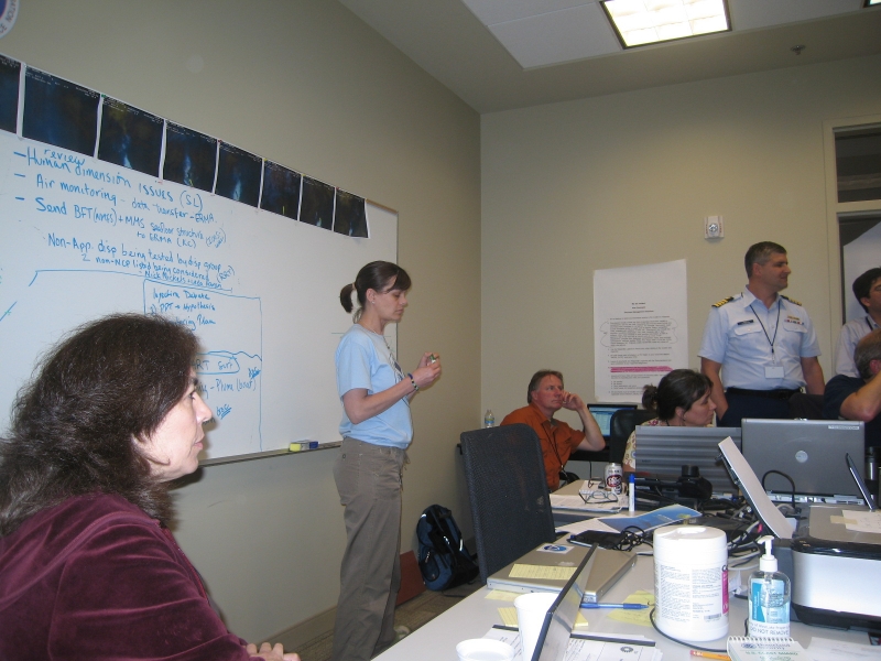 A group of people in a conference room area with a whiteboard.