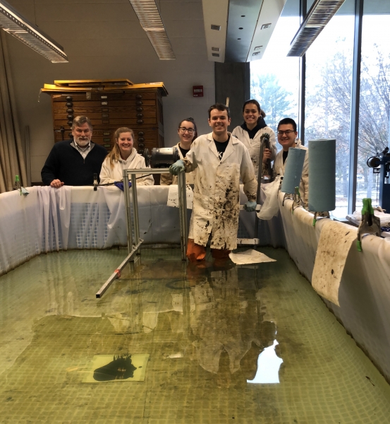 A group of people standing in and behind a small pool of water. 