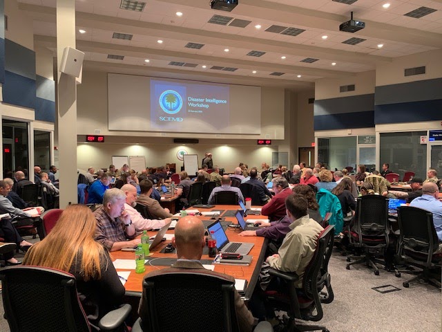 A conference room full of people looking at a screen.