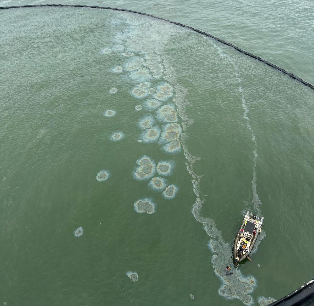 Aerial image of oil emerging in an area of containment boom. A response vessel is seen in the lower right of the image.