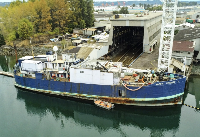 A large derelict fishing vessel tied up in a waterway.