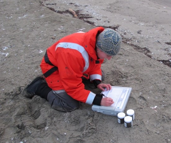 A woman leaning on the ground writing in a notebook.