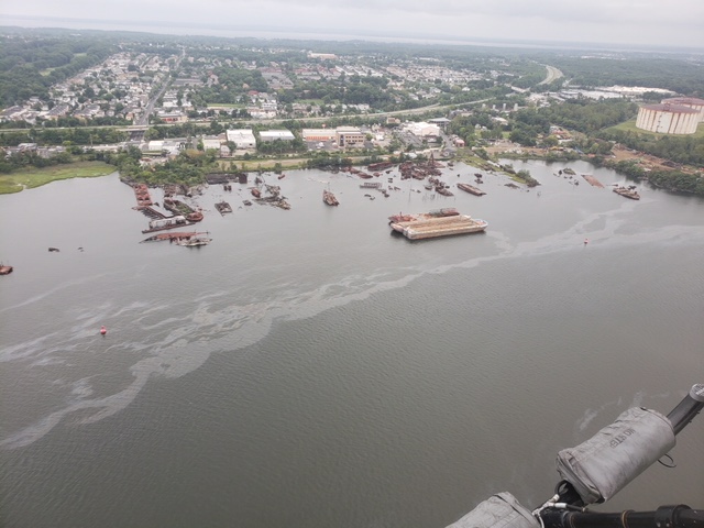 An aerial view of an oil sheen stretching across a river shoreline.