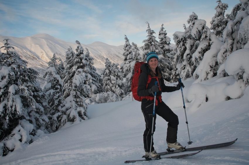 A woman on skiis with a snowy mountain scene in the background.