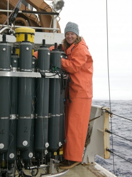 A woman in an orange snowsuit on a boat. 