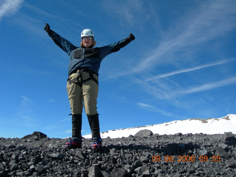 A woman on a mountain with her hands in the air. 