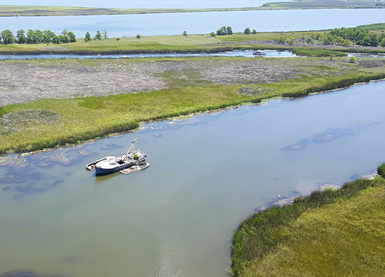 An aerial view of an abandoned vessel in a river. 