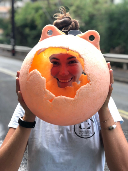 A person holding up a foam ball and looking through a hole in it.